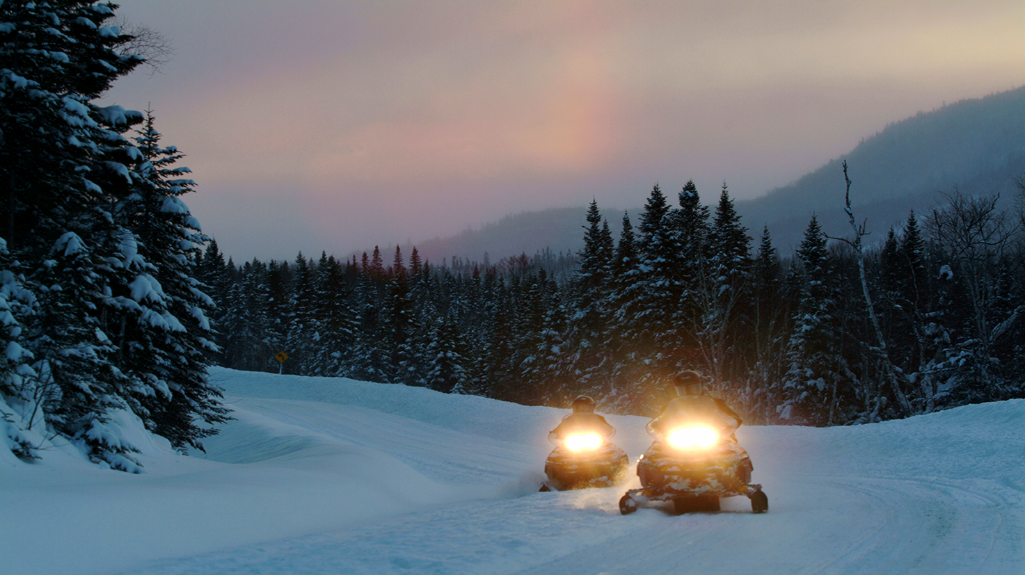 Conduite de motoneiges au Canada pendant une soirée d’hiver.